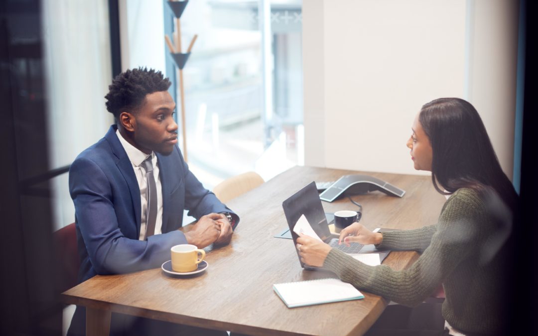 Woman interviewing a young man for a position and using the tips for interviewers to ensure a great interview happens.